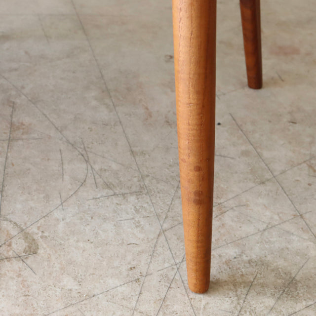 Close-up of tapered teak leg from vintage mid-century Danish dining chair showing smooth wood grain and warm finish on.