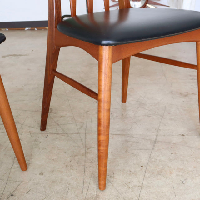 Mid-century Danish vintage teak dining chair with tapered legs and black upholstered seat.
