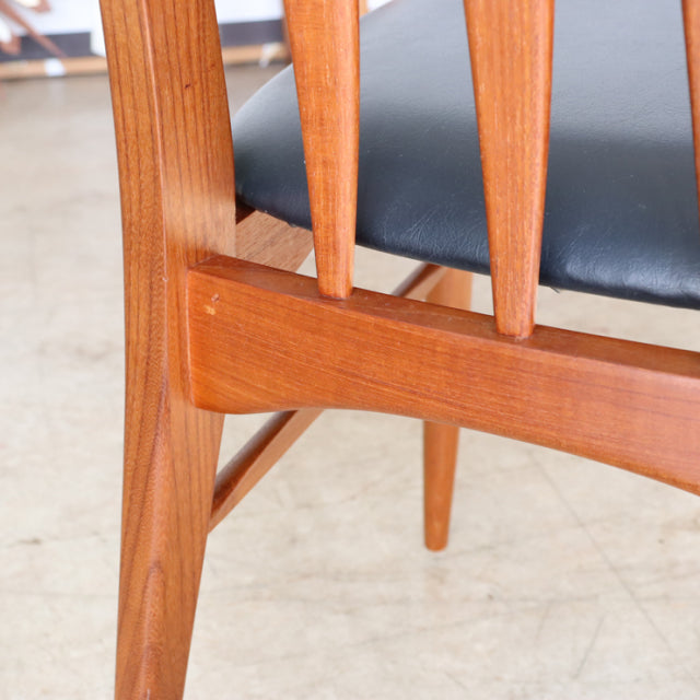 Mid-century vintage teak dining chair from Denmark with slender angled legs and black upholstered seat.