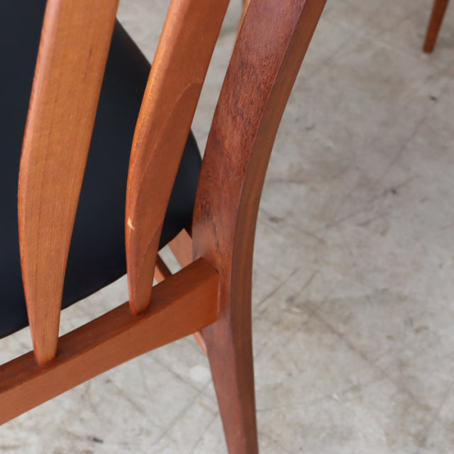 Set of four vintage mid-century Danish dining chairs in warm teak with curved backrests and tapered legs, showcasing rich.