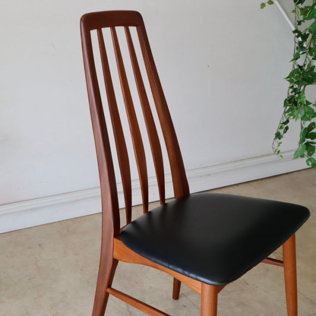Set of four vintage mid-century Danish dining chairs in teak with tall slatted backs and black leather seats.