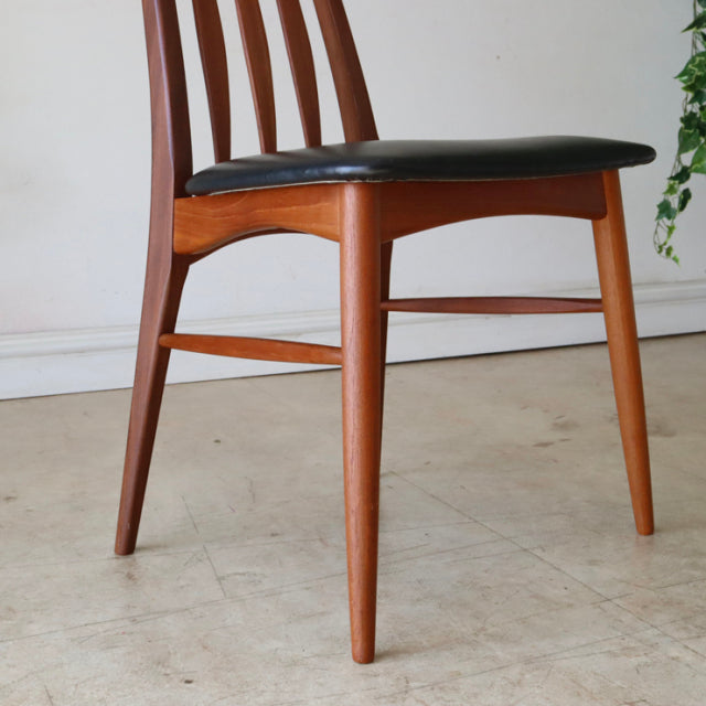 Set of four vintage mid-century Danish dining chairs with teak wood frames and black leather upholstered seats, featuring.