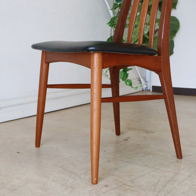 Vintage mid-century Danish dining chair in teak with black leather cushioned seat and tapered legs.