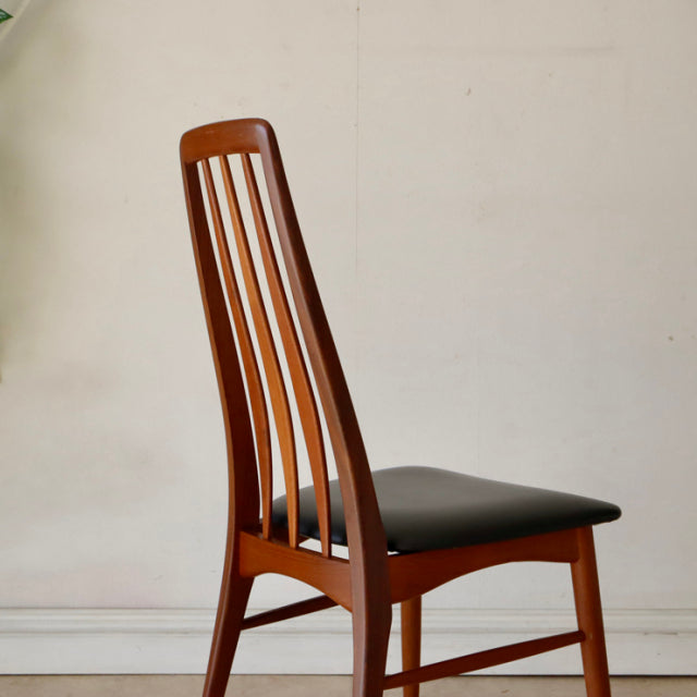 Set of four vintage teak dining chairs from mid-century Denmark with sleek British design, tall slatted backs and black.