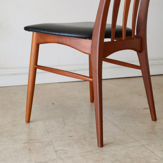 Set of four vintage mid-century dining chairs from Denmark made of warm teak wood with visible grain and black upholstered.