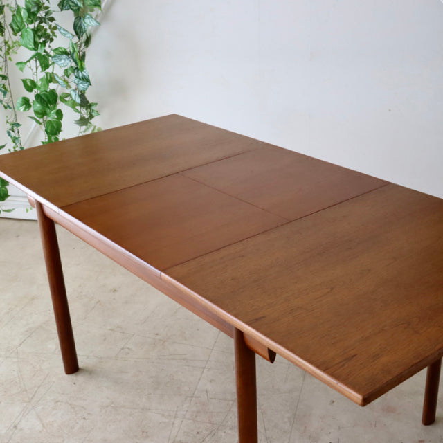 Vintage British mid-century teak dining table with smooth wood grain, tapered round legs, and rectangular top from.