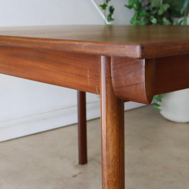 Mid-century British vintage teak dining table with smooth wood grain, rounded edges, and tapered legs from Whiteandnewton.