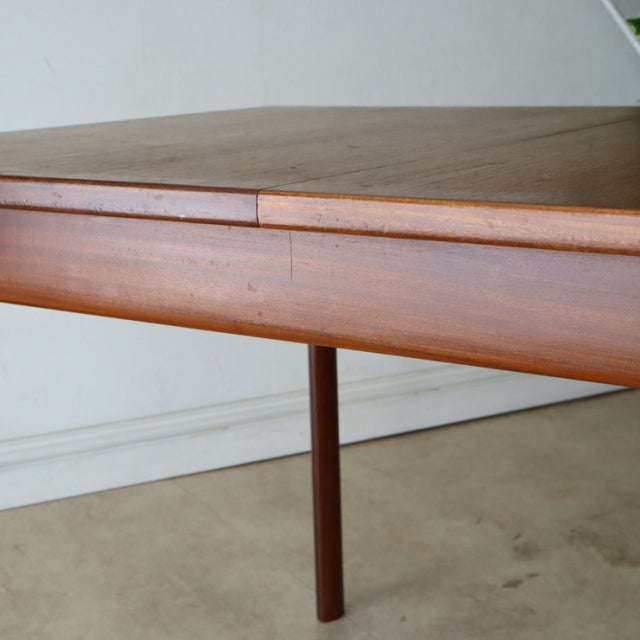 Vintage British mid-century teak dining table with smooth wood grain and slender round legs, classic rectangular design by.