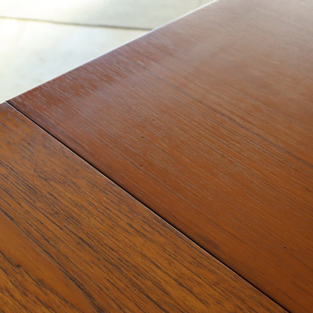 Close-up of vintage British teak dining table top showing smooth mid-century wood grain and neat joinery.