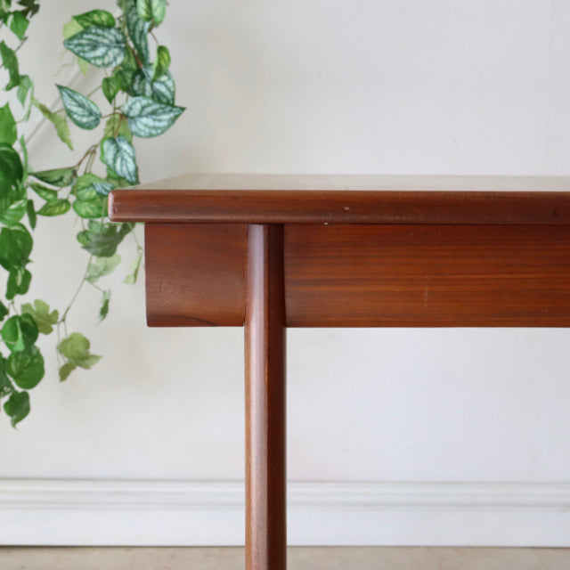 Mid-century British dining table in smooth teak with visible wood grain and slender round legs, vintage Danish style.