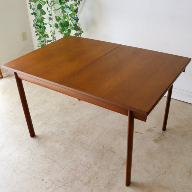 Vintage mid-century British teak dining table by Whiteandnewton with warm wood grain and slender tapered legs.