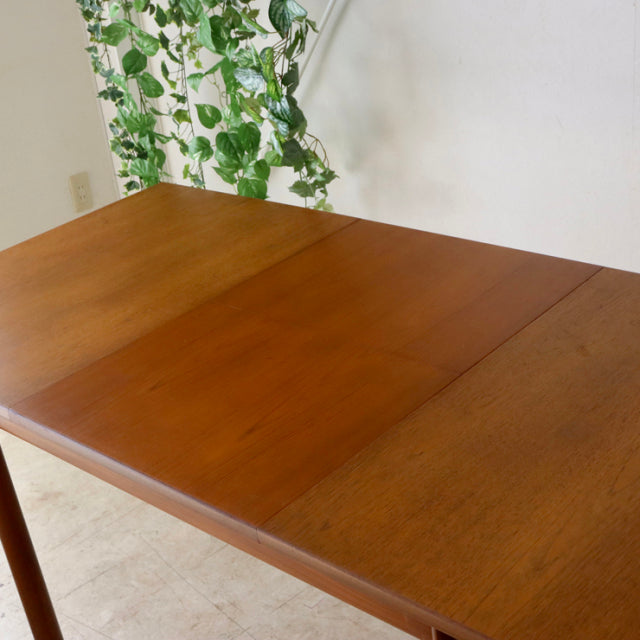 Vintage British mid-century teak dining table by Whiteandnewton with smooth wood grain and slender tapered legs.
