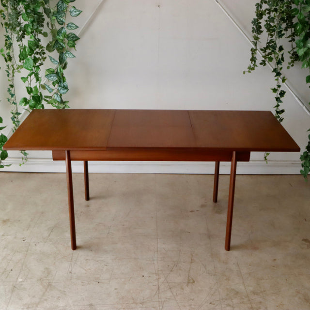 Mid-century British teak dining table by Whiteandnewton with clean lines, slender tapered legs, and smooth wood grain surface.