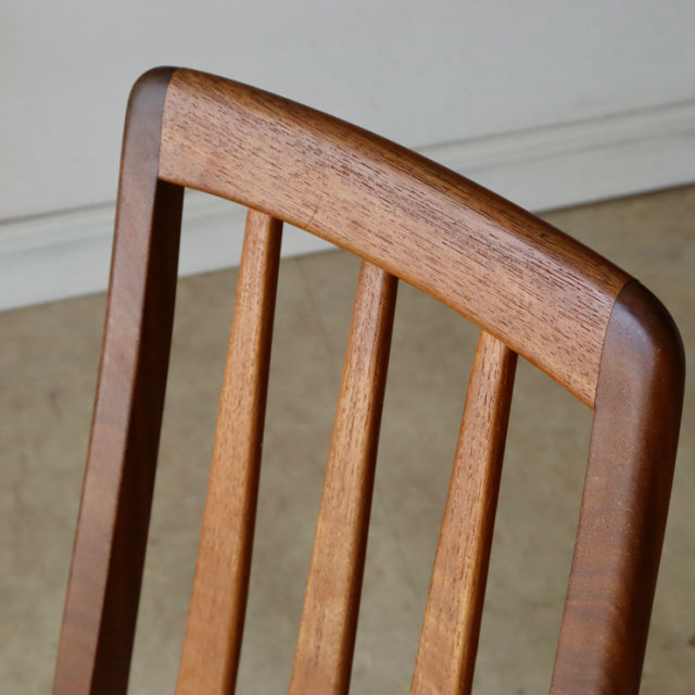 Close-up of vintage KOFOEDS HORNSLET teak dining chair back with curved top rail and three slender vertical spindles in.