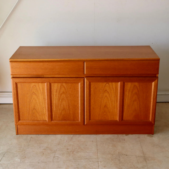 Vintage teak McIntosh British mid-century sideboard with rich wood grain, four paneled doors, and sleek rectangular form.