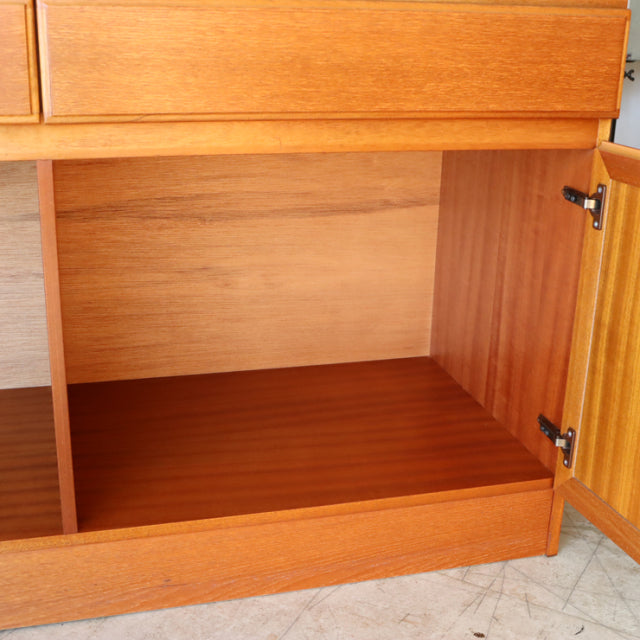Mid-century British teak sideboard by McIntosh with rich wood grain, open storage, and hinged door detailing.
