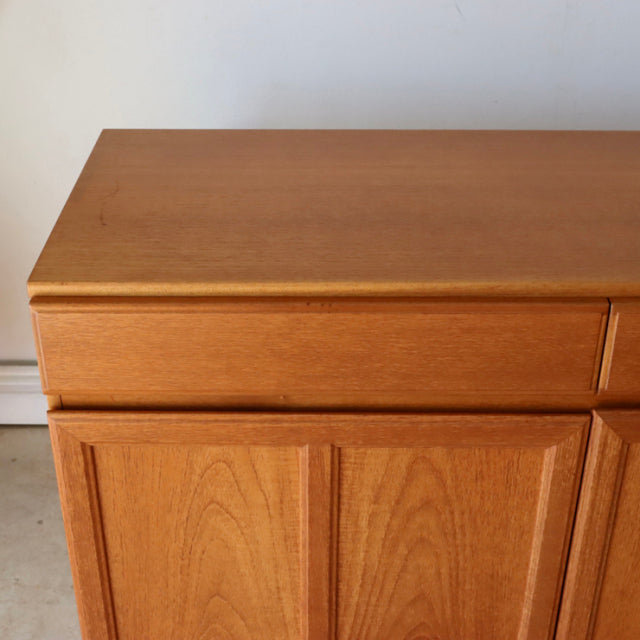 Vintage mid-century British McIntosh teak sideboard with smooth wood grain, clean lines, and tapered legs.