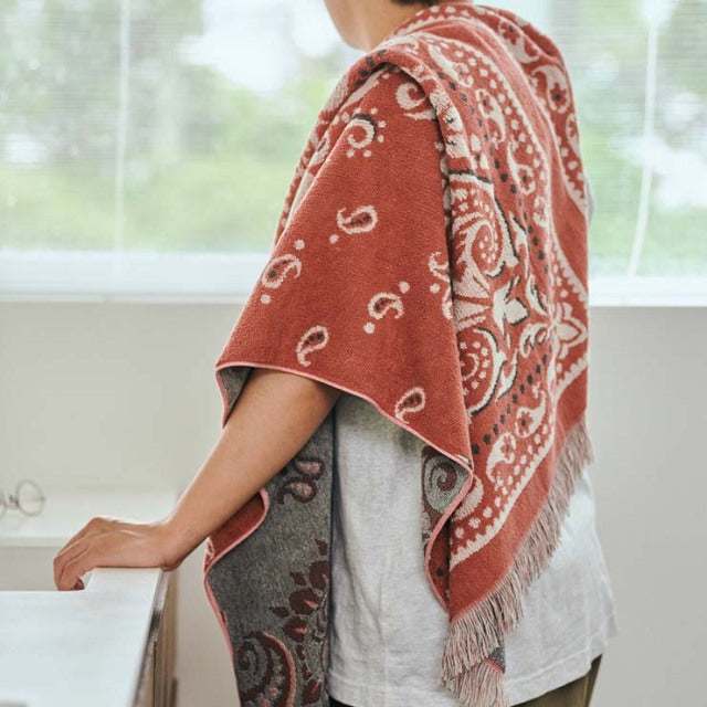Cotton pile blanket in red bandana pattern draped over shoulder, vintage style with fringed edges.