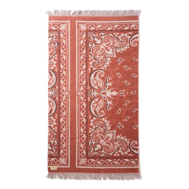 Red cotton pile blanket with intricate white bandana-style patterns and fringed edges, vintage British design.
