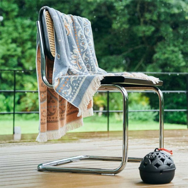 Mid-century chrome cantilever chair with teak cane backrest, draped with a vintage blue and beige cotton pile bandana.