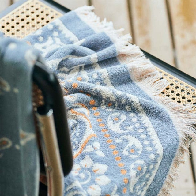 Vintage teak chair with woven cane seat and backrest, mid-century British design, draped with a blue and white.