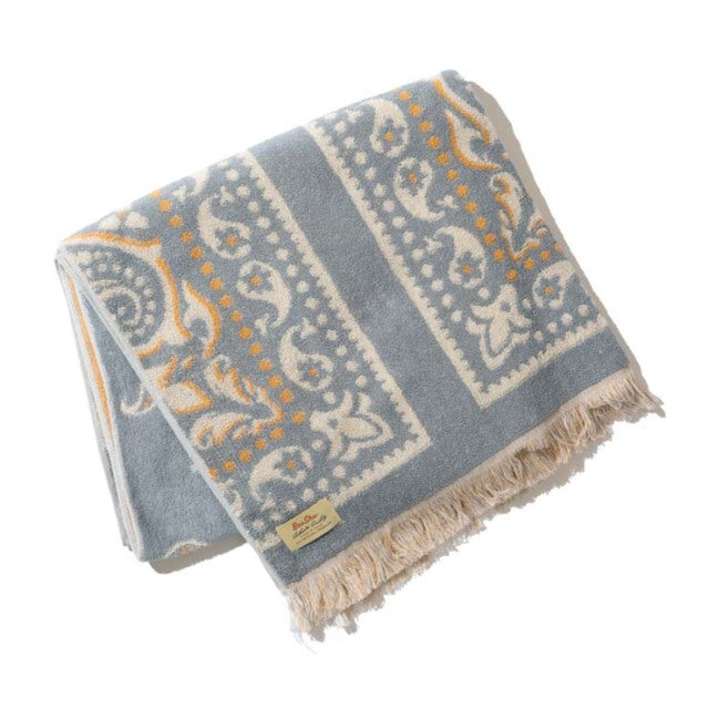 Vintage-inspired cotton pile blanket with blue, beige, and mustard bandana patterns, fringed edges, soft texture, suitable.