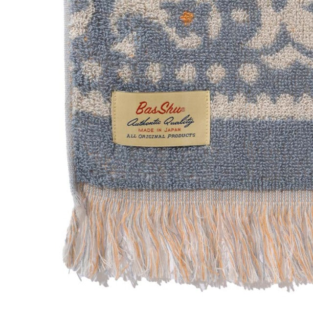 Close-up of vintage cotton pile blanket in blue and cream bandana pattern with soft fringe and Basshu brand label sewn on.