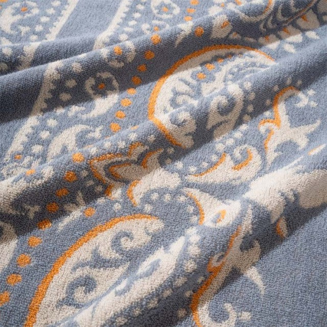 Soft cotton pile blanket featuring vintage British bandana pattern in muted sax blue, orange, and white tones.