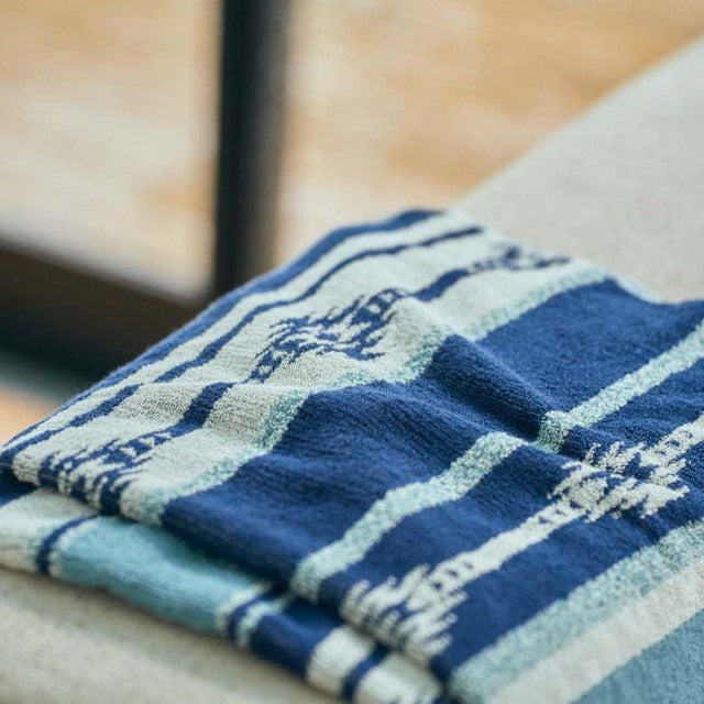 Blue and white vintage cotton pile blanket with native border pattern draped over mid-century teak furniture.