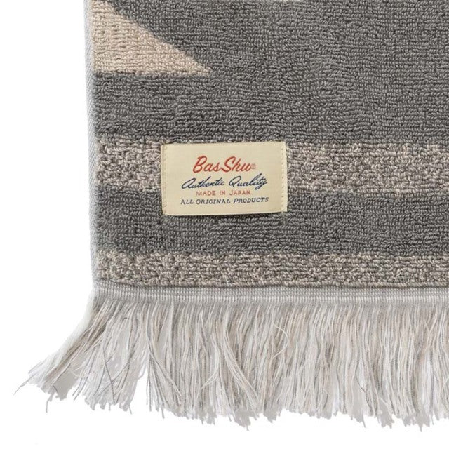 Beige cotton pile blanket with native motif, fringe edge, and vintage British Basshu label.