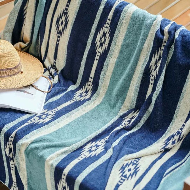 Blue and beige striped vintage cotton pile blanket with native border pattern draped over teak mid-century British vintage.