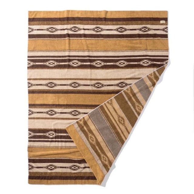 Brown cotton pile blanket with native border pattern, vintage style, folded corner showing reverse side with muted stripes.