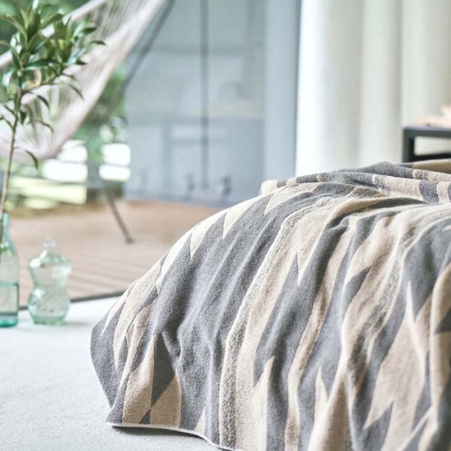 Mid-century teak British vintage blanket draped over furniture with beige and gray native motif pattern, soft cotton pile.