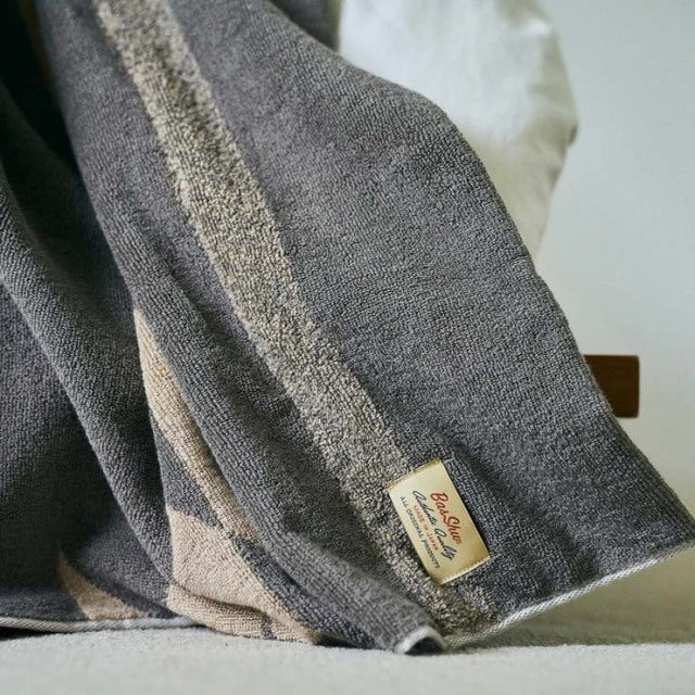 Beige cotton pile blanket with native motif, soft texture, vintage style, draped on teak British mid-century furniture.