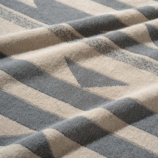 Beige cotton pile blanket with native-inspired gray geometric patterns, soft textured fabric.