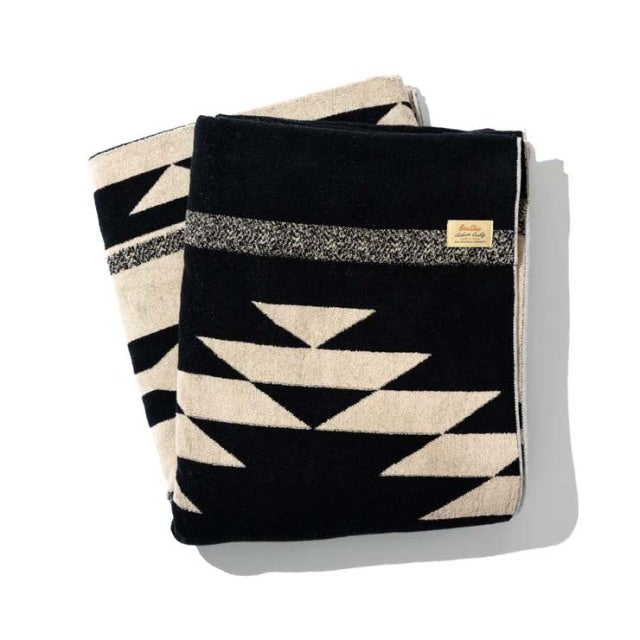 Black and beige cotton pile blanket with bold native geometric motif, vintage British style, soft textured fabric, folded.
