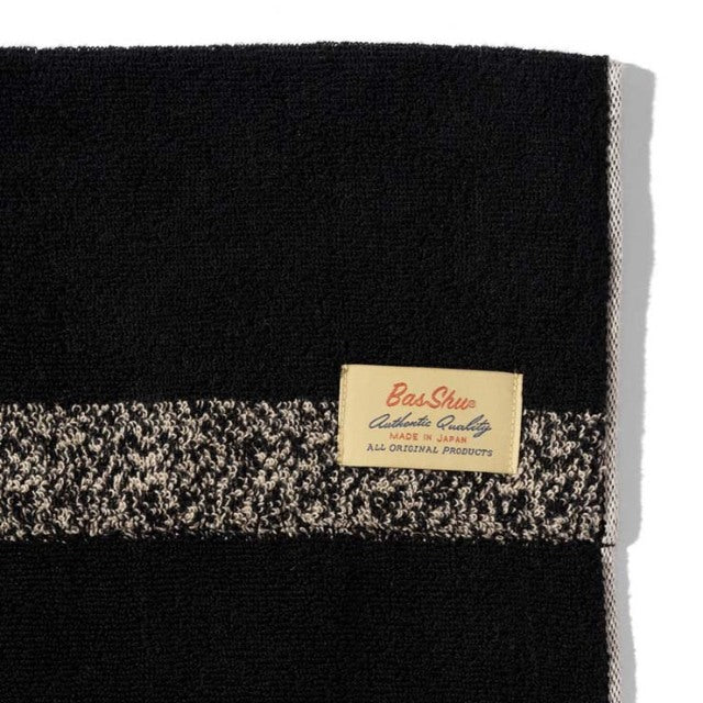Black cotton pile blanket with speckled beige stripe and Basshu brand label, vintage style.