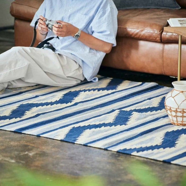 Blue and white patterned vintage cotton rug with geometric designs, paired with mid-century teak British vintage leather.