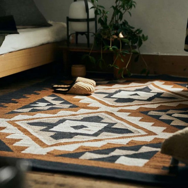 Vintage mid-century teak bed frame with clean lines and tapered legs on a patterned British-Denmark inspired cotton rug.