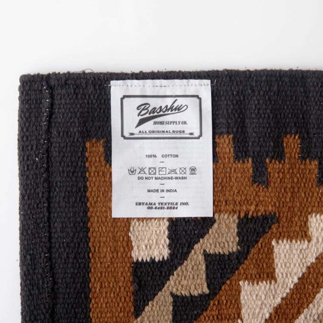 Basshu branded black and brown cotton rug label with care instructions and detailed weaving on vintage mid-century style.
