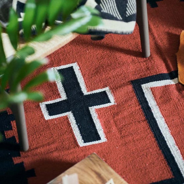 Vintage British cotton rug in warm terracotta with black and white geometric patterns, styled with mid-century teak.