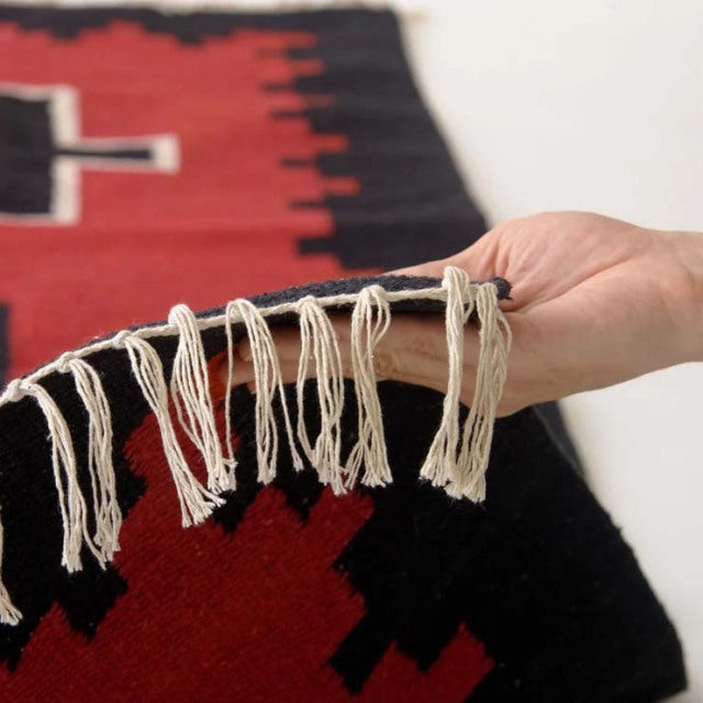 Handwoven vintage cotton rug with red, black, and beige geometric patterns and natural fringe, British mid-century style.