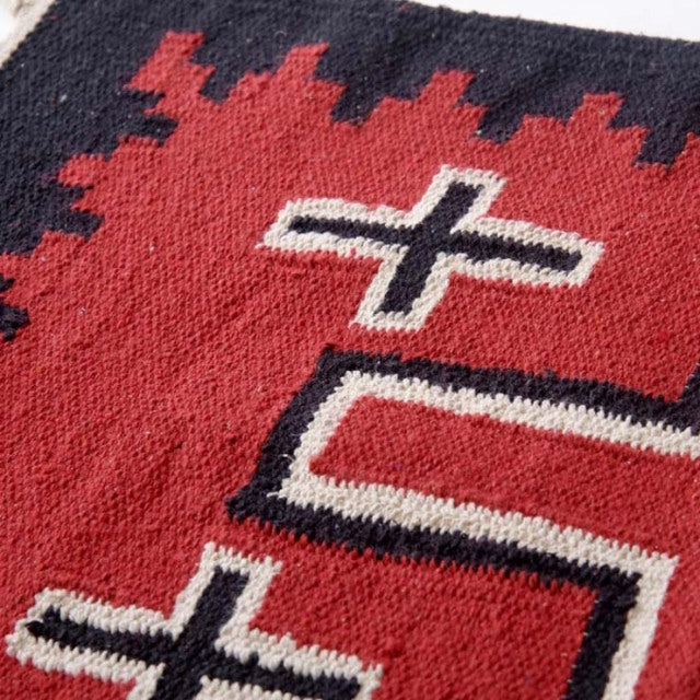 Close-up of vintage-inspired cotton rug with bold red, black, and white geometric pattern, highlighting textured weave and.