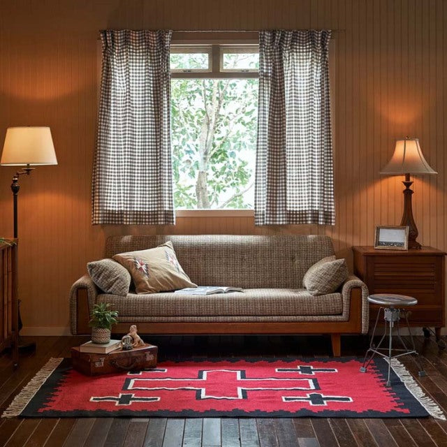 Mid-century British teak sofa with clean lines and visible wood grain, paired with a vibrant vintage cotton rug featuring.