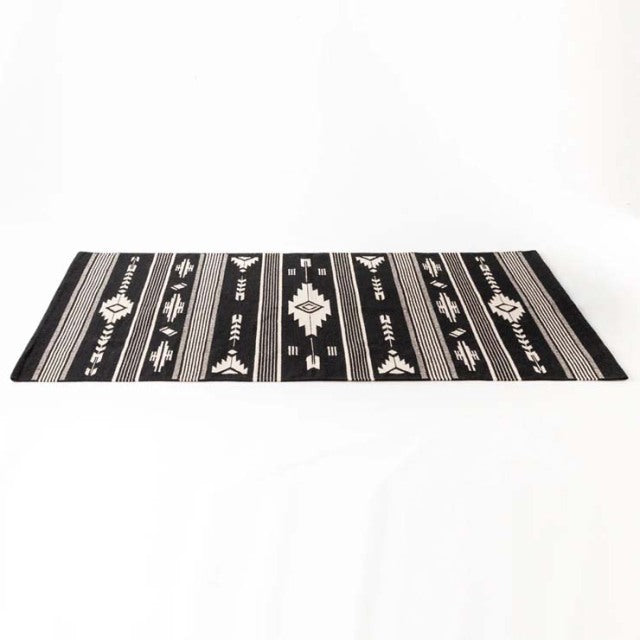 Black and white vintage cotton rug with geometric patterns from British mid-century style, flat-woven texture.