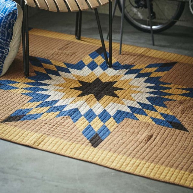 Vintage patchwork quilt cover in camel tones with geometric star pattern, mid-century British vintage style.