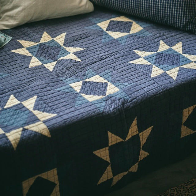 Blue patchwork quilt cover with star patterns, vintage British mid-century style, textured fabric.