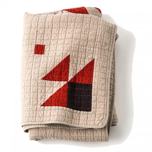 Beige patchwork quilt with red and dark brown geometric shapes, vintage British style, textured stitching.