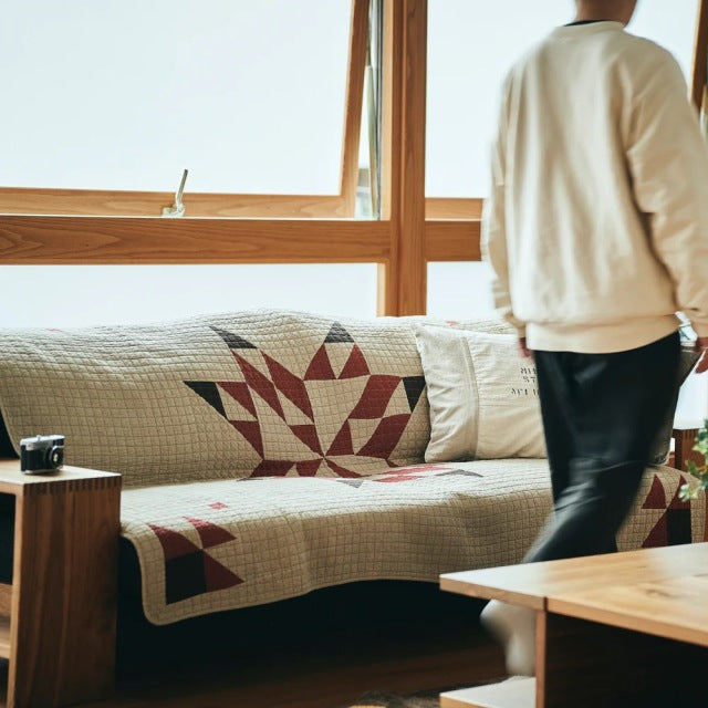 Mid-century British vintage teak sofa with visible wood grain and red-beige patchwork quilt cover, paired with teak side and .