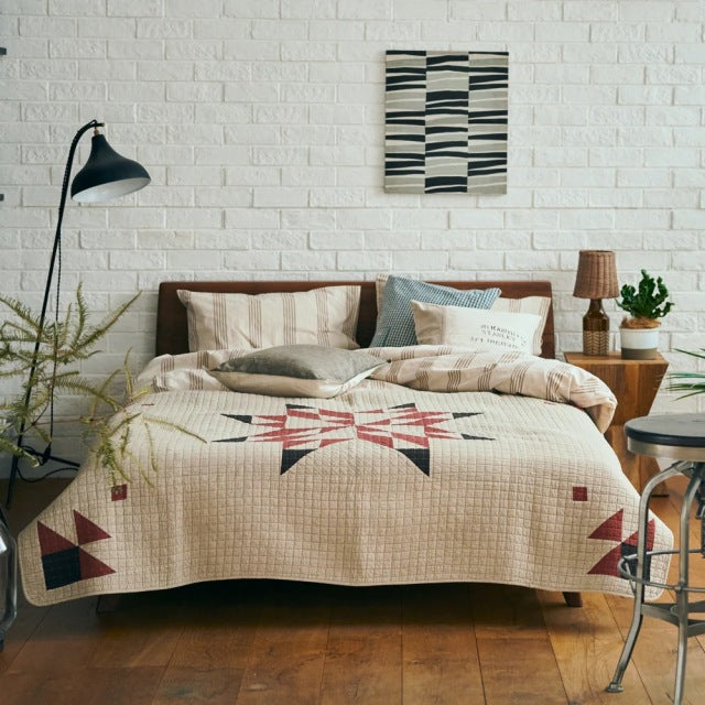Mid-century teak bed frame with visible wood grain, paired with British vintage-style patchwork quilt cover in beige.